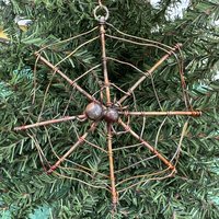 copper spiderweb ornament on tree