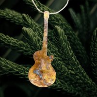 Copper electric guitar ornament on pine branch background
