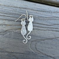 Sterling cat earrings on flat surface