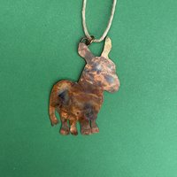 Copper donkey silhouette ornament, green background.
