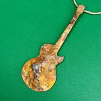 Copper electric guitar ornament on green background