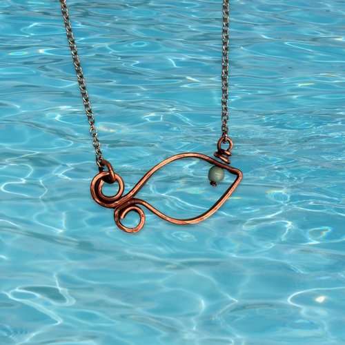 Copper fish necklace, water background.
