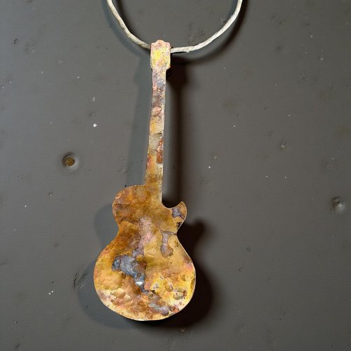 Copper electric guitar ornament on gray concrete background