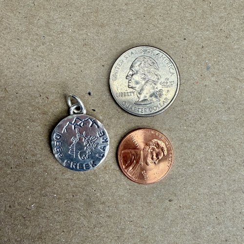 Deep Creek Lake charm next to penny and quarter coins to show size