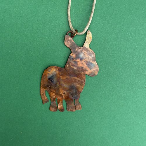 Copper donkey silhouette ornament, green background.